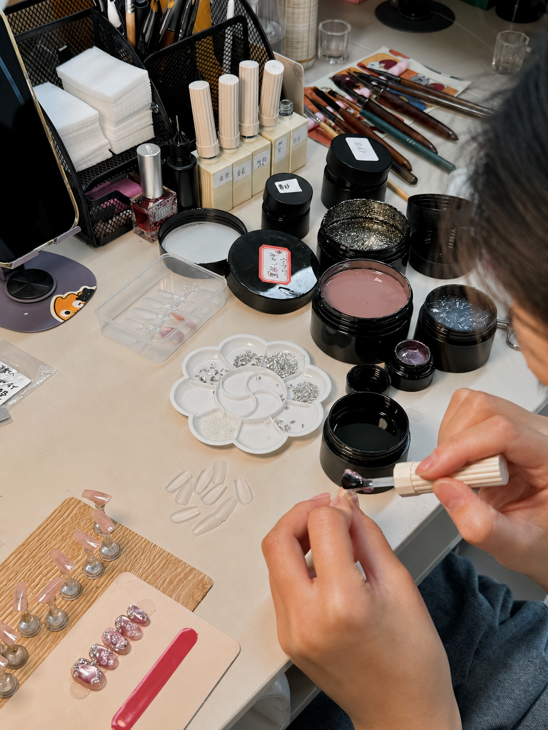 Hand-painting detailed press-on nail art at the Silstat Nails workbench